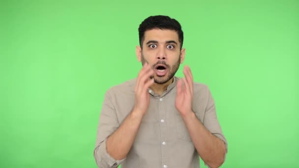 Emotional amazed brunette man with bristle in shirt clutching his face and screaming in surprise, shouting oh my god wow, reaction to crazy shocking news. studio shot, green background, chroma key - Filmati, video
