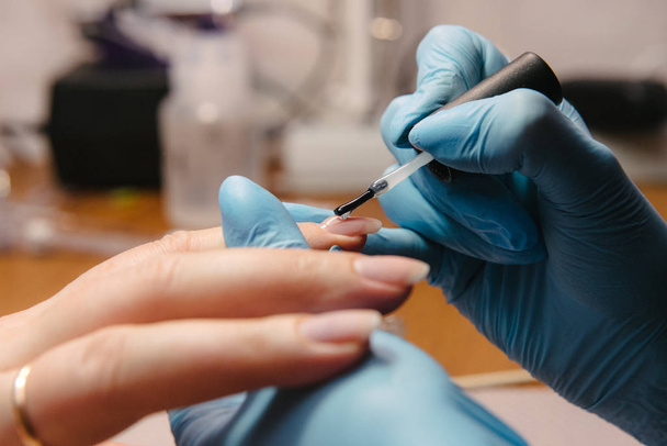 Manicurist makes hardware manicure close-up. Treatment of nails with the help of hardware manicure - Foto, imagen