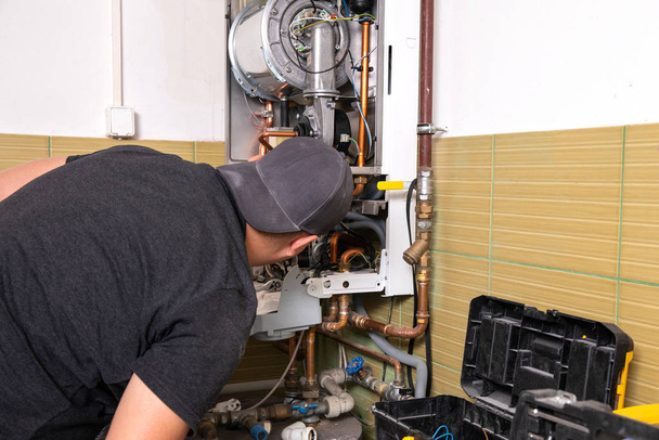 中央加熱システムを固定する配管工、ガスボイラーを提供する労働者 - 写真・画像