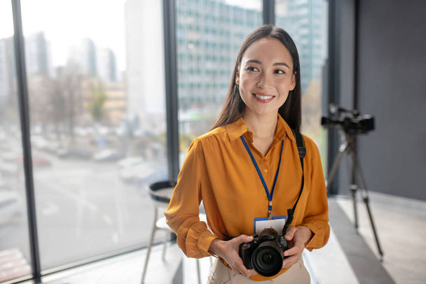Dark-haired young cute reporter holding a camera - Фото, изображение