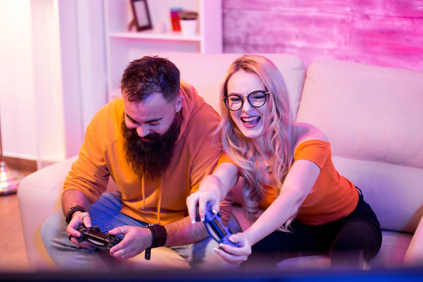 Beautiful young couple entertaining themselves playing online video games - Photo, Image
