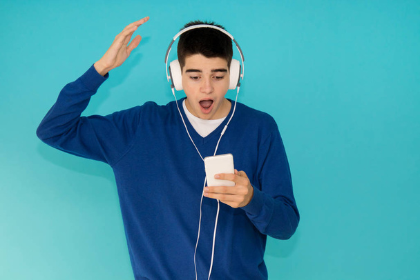 fiatal tizenéves férfi mobiltelefon és divatos fejhallgató elszigetelt színes háttér - Fotó, kép