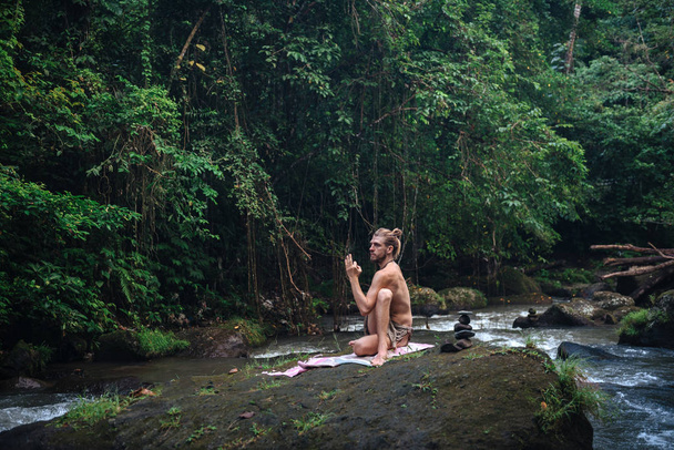Yoga practice and meditation in nature. Man practicing near river - Foto, imagen