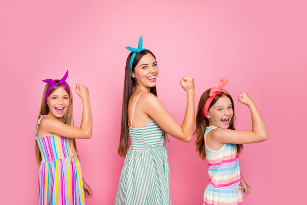 Portrait of cheerful family raising their fists screaming yeah celrbrating victory wearing bright dress skirt isolated over pink background - Foto, Imagen