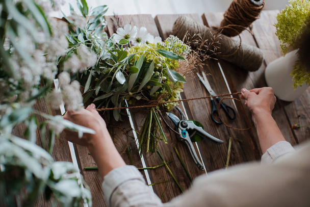 Female professional florist prepares the arrangement of wild flowers. - Photo, Image
