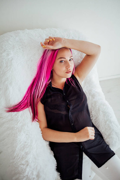 the girl with the pink hair is sitting in a white armchair - Photo, image