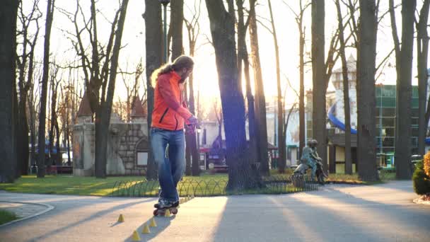 Rollers are a mans favorite hobby. A professional roller masterfully performs a difficult ride on the pavement of a city park in the sunny weather of an autumn day. Bottom-up shooting in slow motion. - Footage, Video