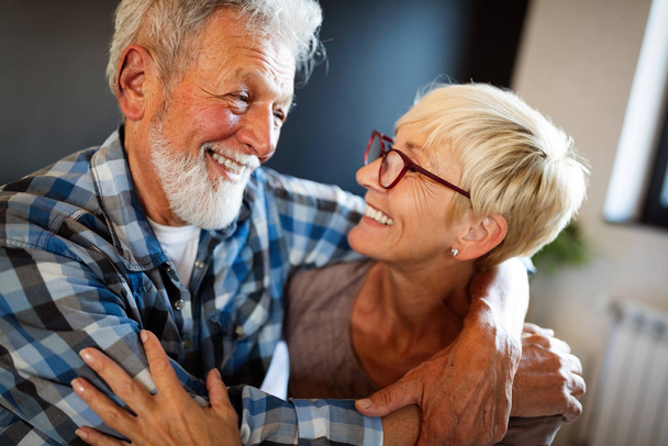 Happy romantic senior couple hugging and enjoying retirement at home - Фото, изображение