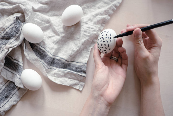 mãos que traçam o modelo monocromático geométrico em ovos de Páscoa. conceito de férias de Páscoa
 - Foto, Imagem