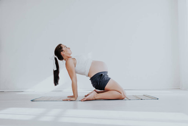 a pregnant woman is engaged in gymnastics and yoga - 写真・画像