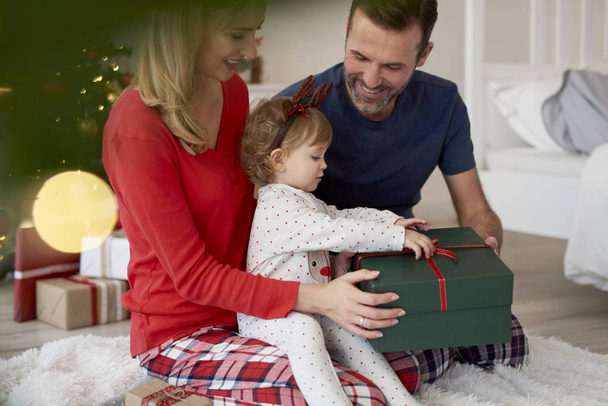 Дитина відкриває різдвяний подарунок з батьками
 - Фото, зображення