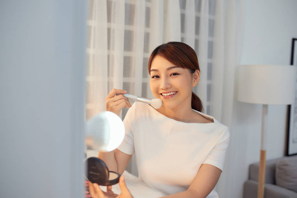 Happy young Asian woman applying makeup on face with big brush - Zdjęcie, obraz