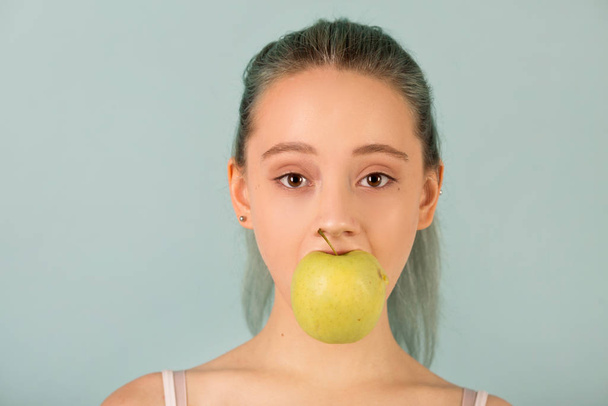 beautiful slender young woman in sportswear bites an apple - Photo, Image