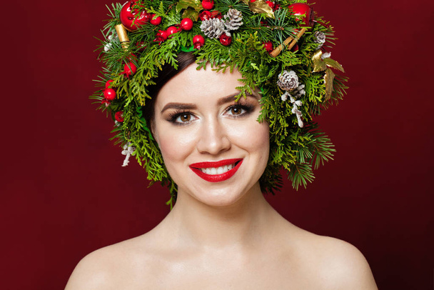 Hermosa mujer con decoraciones navideñas sobre fondo rojo
 - Foto, imagen