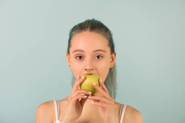 beautiful slender young woman in sportswear bites an apple - Photo, Image