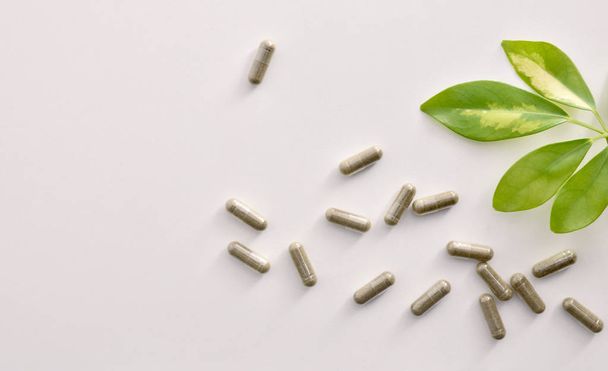 Background with capsules and plant on white table top view - 写真・画像