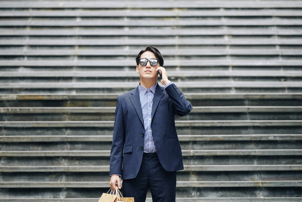 Portrait d'un homme d'affaires sérieux dans des lunettes debout dans les escaliers et faisant un appel téléphonique
 - Photo, image