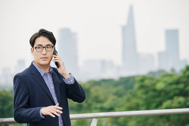 Ritratto di imprenditore di successo in occhiali che discute questioni importanti con il partner commerciale quando si trova in piedi sul ponte
 - Foto, immagini