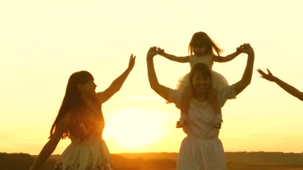 Χαρούμενη παιδική ιδέα. Ευτυχισμένη νεαρή οικογένεια με ένα παιδί τρέχει σε όλη την περιοχή κατά την πτήση στο φως του ηλιοβασιλέματος. Μητέρα και κόρες περπατούν στο πάρκο και παίζουν στο λιβάδι στον ήλιο. έννοια της ζωής μιας μεγάλης οικογένειας - Πλάνα, βίντεο
