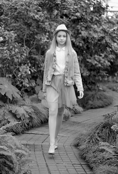 молода дівчина з довгим білим волоссям в капелюсі і джинсова куртка гуляє в саду
  - Фото, зображення