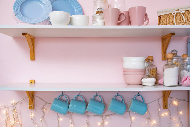 Imagen de decoración de interiores de Navidad de estante de cocina con tazas y guirnalda vista de fondo interior
 - Foto, imagen