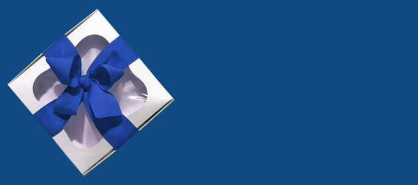 Caixa de presente metálica prata com um laço de fita azul isolado no fundo branco. Espaço de cópia, mockup, flatlay, vista superior
. - Foto, Imagem