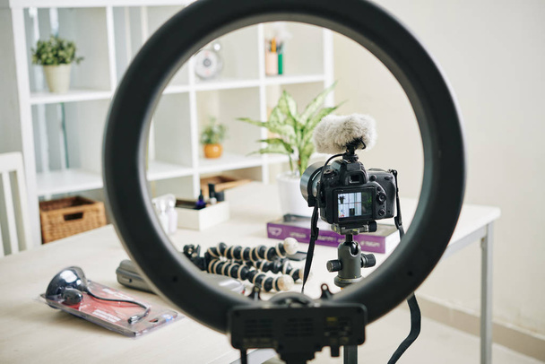 Circle lamp, digital camera and monopods in office of professional blogger - Photo, Image