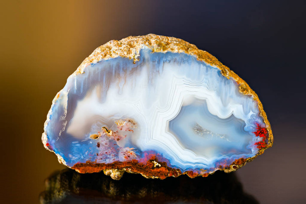 White blue agate gem cross section with reflection on dark colored background - Фото, зображення