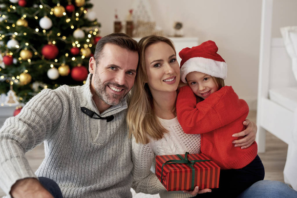 Portret uśmiechniętej rodziny z prezentem świątecznym - Zdjęcie, obraz