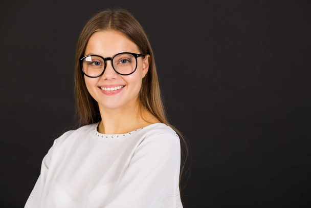 beautiful young woman in glasses on a black background - Zdjęcie, obraz