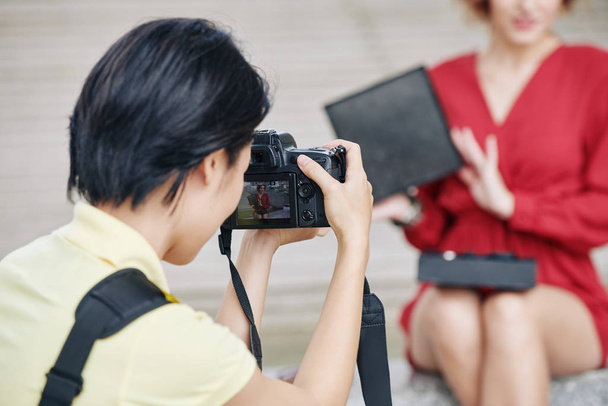 Photographer shooting female blogger showing beauty box she created for subscribers, focus on digital camera - Valokuva, kuva