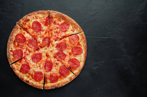 szeletelt pepperoni pizza fekete alapon - Fotó, kép