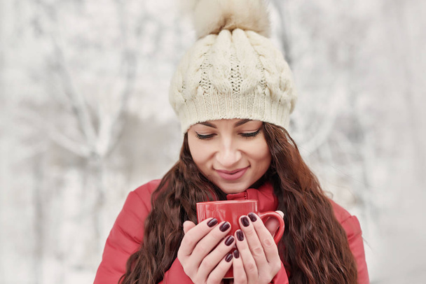 Mujer bebe té caliente o café de la taza en Cozy Snowy House Garden en la mañana de invierno. Hermosa chica disfrutando de invierno al aire libre con taza de bebida caliente. Vacaciones de Navidad. Acogedor estilo de vida invierno
. - Foto, Imagen
