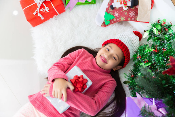 Malá asijská dívka úsměv ležící na koberci s vánočním dárkem, N - Fotografie, Obrázek