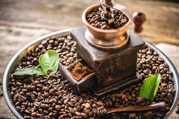 Molino de café de la cosecha de madera y mojo en una pila de granos de café marrón. Café recién tostado con fragancia - Foto, Imagen
