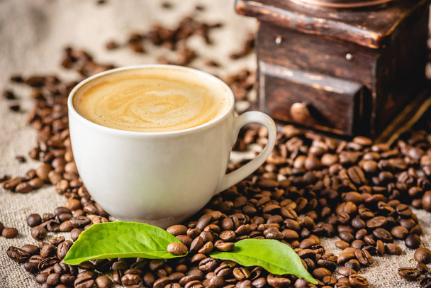 Tasse de café avec mousse et moulin à café vintage en bois. Boisson vivifiante parfumée à base de haricots fraîchement rôtis. - Photo, image
