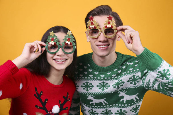 Couple of young people wearing ugly christmas sweaters, posing over colorful isolated background. - Fotó, kép