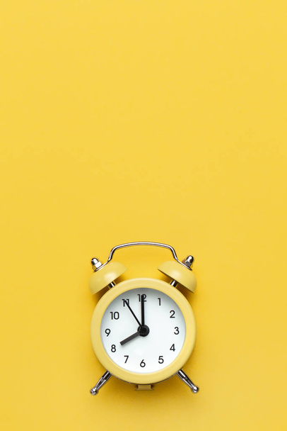 Yellow round alarm clock on the yellow background. - Foto, Bild