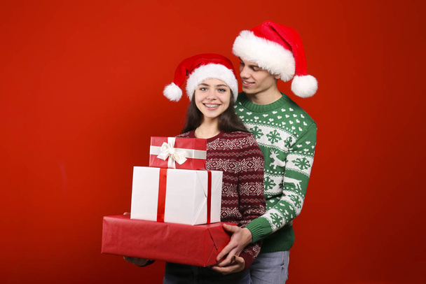 Couple of young people wearing ugly christmas sweaters, posing over colorful isolated background. - Zdjęcie, obraz