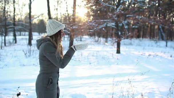 Blowing snow in winter forest enjoying walk. Woman having fun outdoors. Seasonal activities. Girl laughing and relaxing wearing warm clothes - 映像、動画