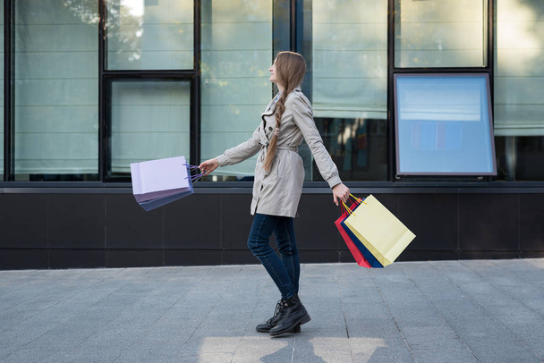 Gelukkige jonge vrouw shopaholic met kleurrijke tassen in de buurt van winkelcentrum. Wandelen op straat. - Foto, afbeelding