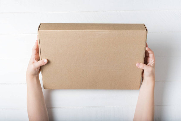 Rectangular cardboard box in children's hands. Top view, white background - Photo, Image