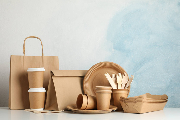 Vaisselle et sac en papier respectueux de l'environnement sur table blanche, espace pour
 - Photo, image