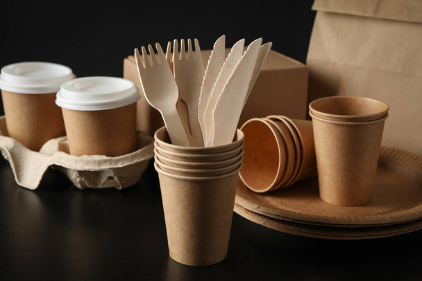 Eco - friendly dishware and paper bag on black background, close - Photo, Image