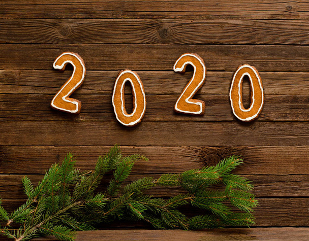 Liczba 2020 wykonana z piernikowych ciastek na drewnianym tle. Gałązki świerkowe. Koncepcja nowego roku - Zdjęcie, obraz
