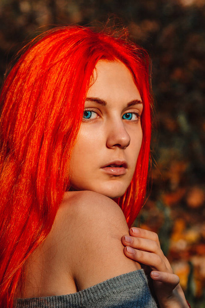 Sexy beautiful redhead girl with long, strong and thick hair. Perfect woman portrait on a background of autumn foliage. Gorgeous deep blue eyes. Natural beauty, clean skin, face and hair care. - Photo, image
