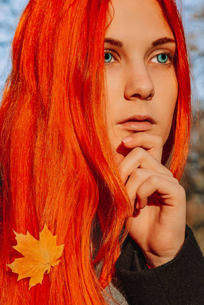 Sexy beautiful redhead girl with long, strong and thick hair. Perfect woman portrait on a background of autumn foliage. Gorgeous deep blue eyes. Natural beauty, clean skin, face and hair care. - Fotoğraf, Görsel