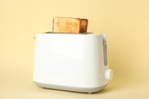 Toaster mit Brotscheiben auf beigem Hintergrund, Nahaufnahme - Foto, Bild