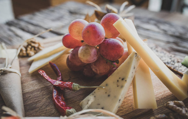 tabla o plato de queso, uvas y frutas. Surtido o varios tipos de queso, y uvas en la mesa en el restaurante. Imagen concepto bodega
 - Foto, Imagen