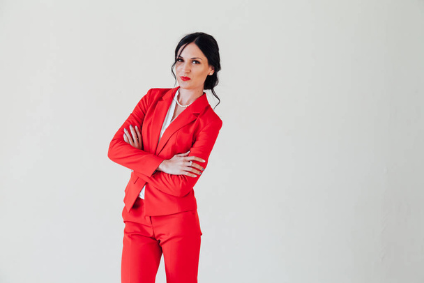 Портрет красивой модной брюнетки в красном деловом костюме в офисе
 - Фото, изображение